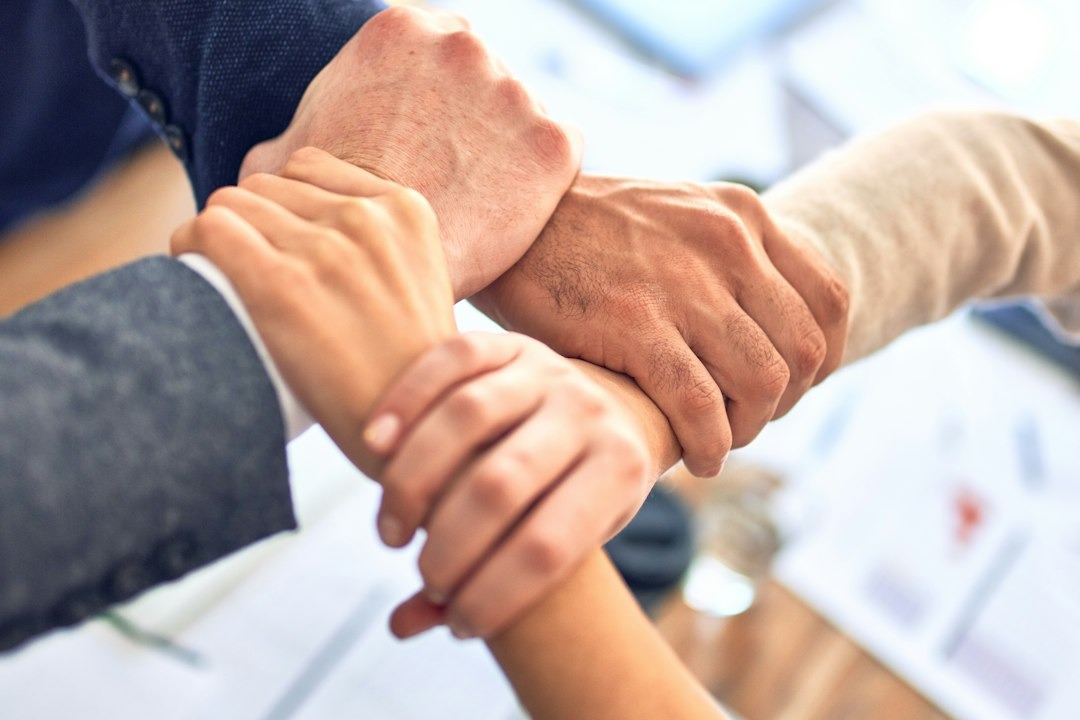 Group of business workers standing with hands together doing symbol at the office